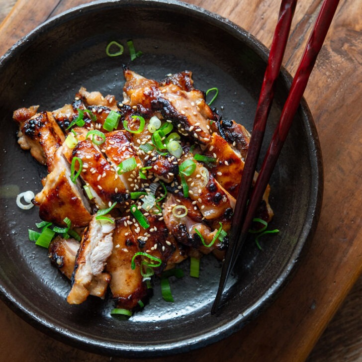 A plate of miso chicken thighs with chopsticks.