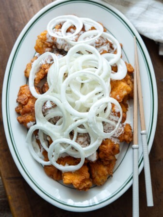 A plate of snow onion chicken with chopsticks.