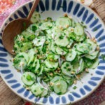Vietnamese cucumber salad in a serving dish with wooden spoon.