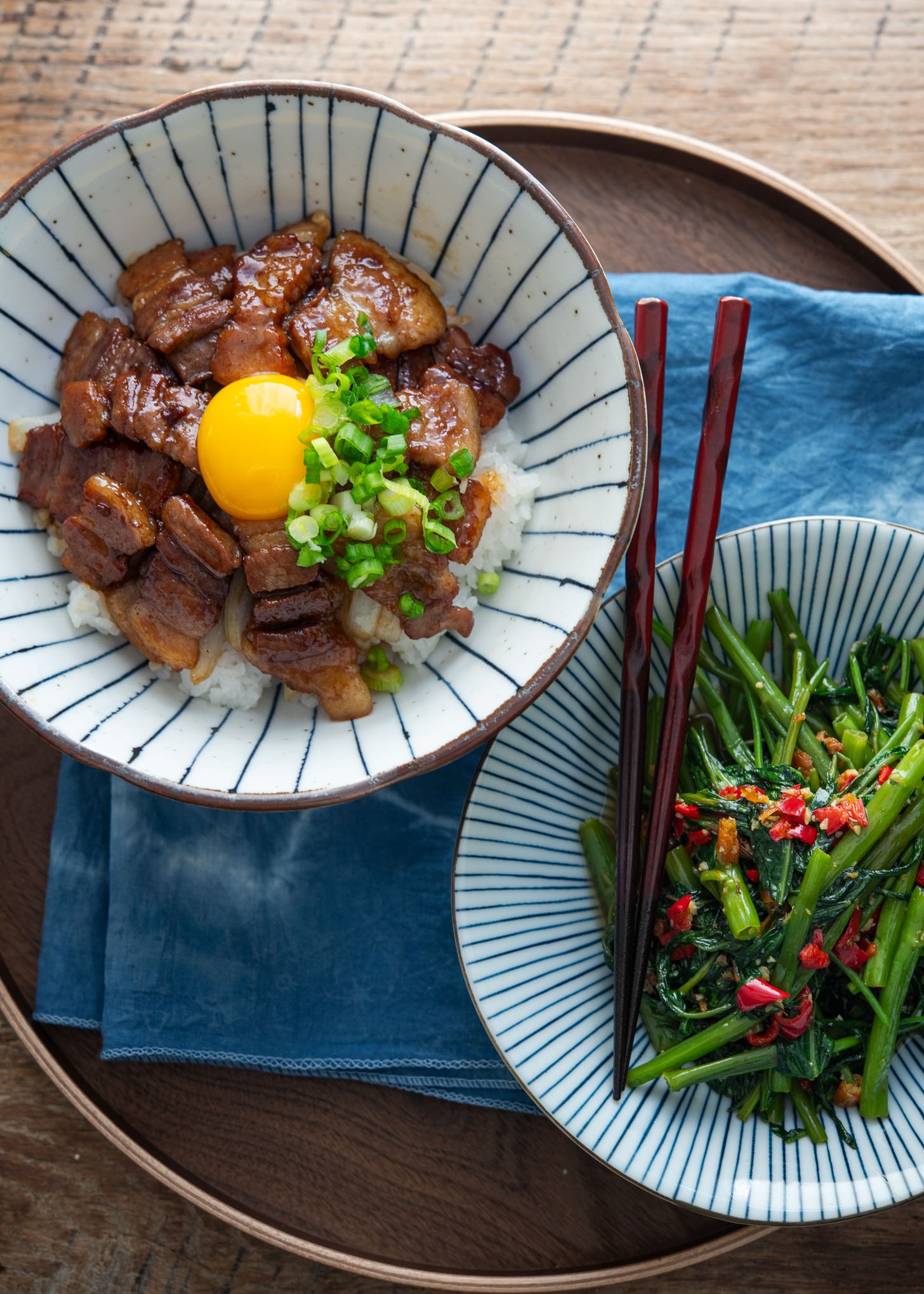 A bow of butadon and a bowl of green veggies served on a tray.