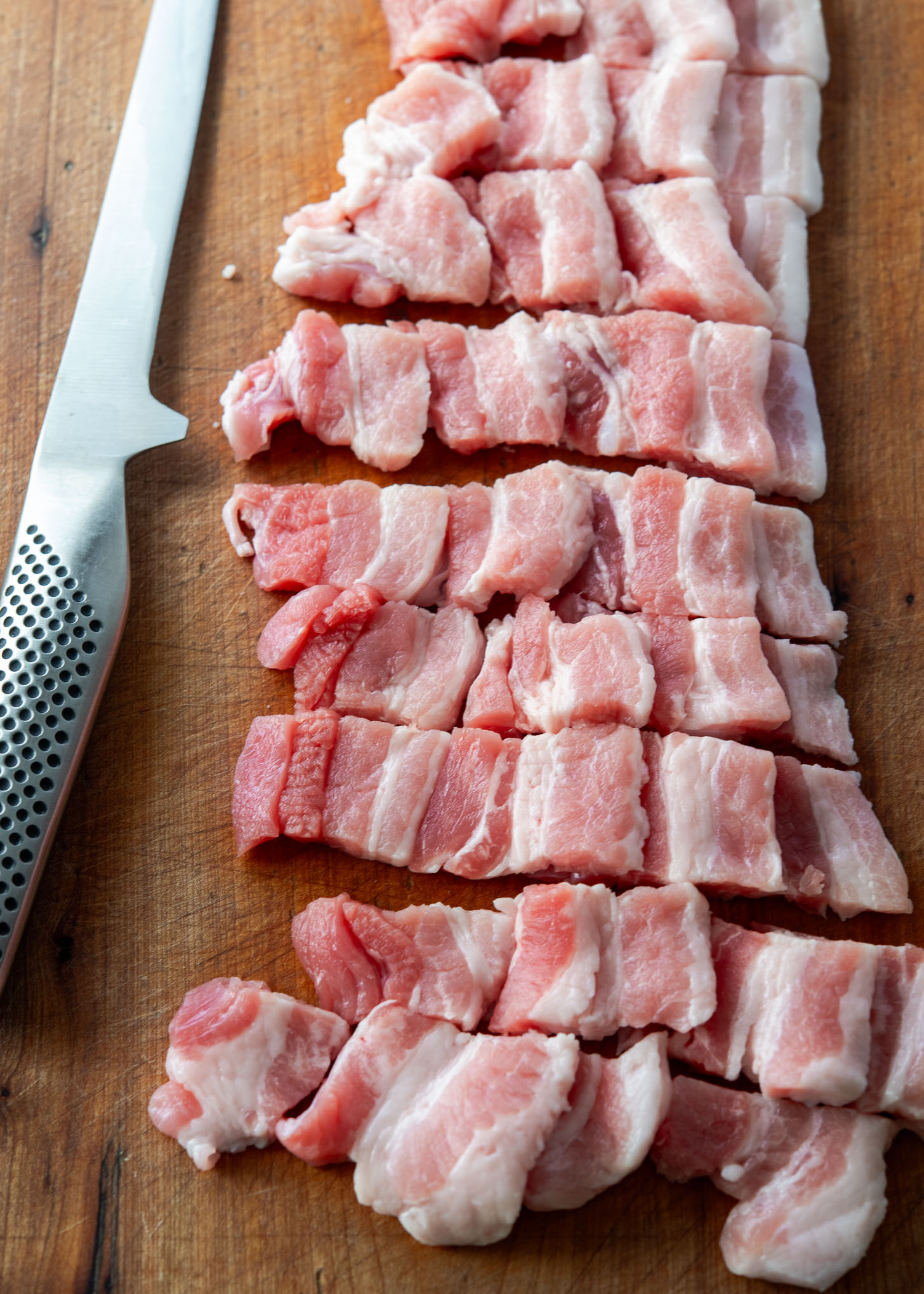 Pork belly sliced on a cutting board.