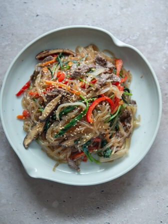 Japchae with colorful veggies and noodles served on a plate.