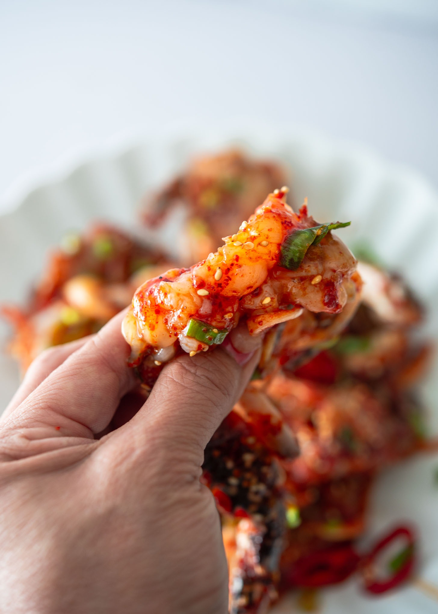 A hand squeezing out the meat from raw marinated crab.