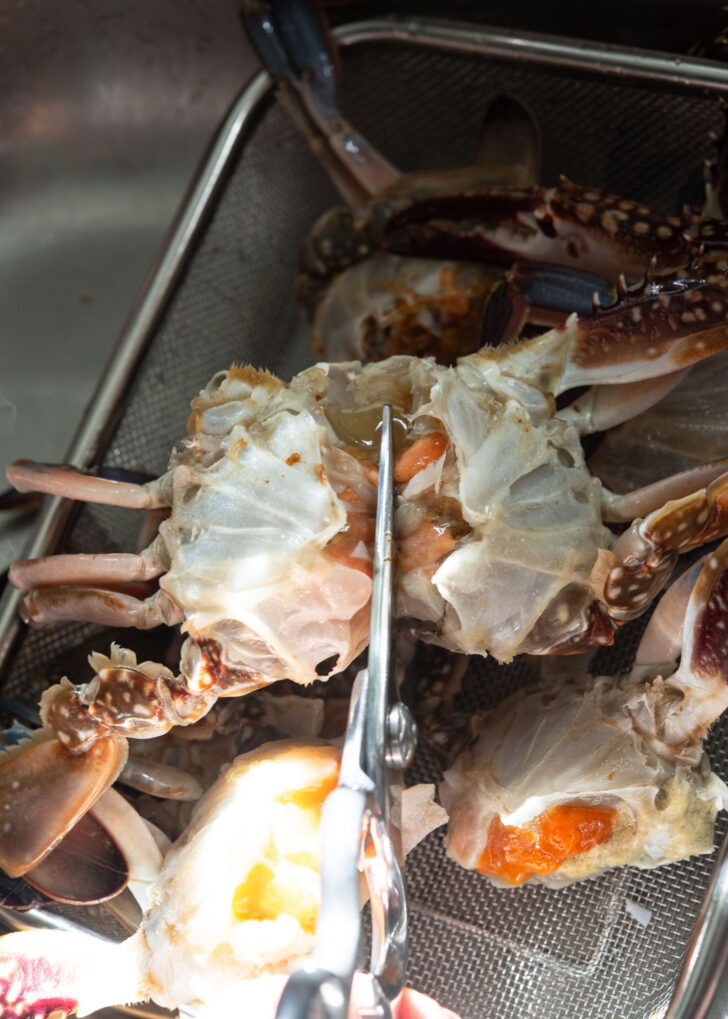 Cutting crab in half using scissors.