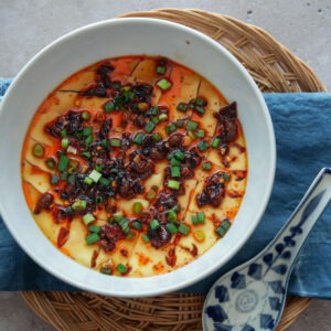 A bowl of Chinese steamed eggs with a spoon.