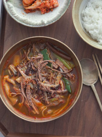 Yukgaejang in a bowl and served with rice and kimchi.