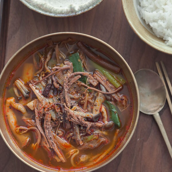 Yukgaejang in a bowl and served with rice and kimchi.