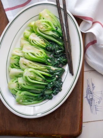 Chinese-style stir-fried bok choy with garlic and glossy sauce on a white plate.