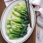 Chinese-style stir-fried bok choy with garlic and glossy sauce on a white plate.