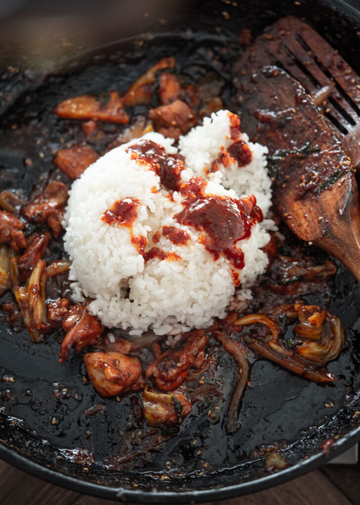 Cooked rice added to leftover dakgalbi in a pan.