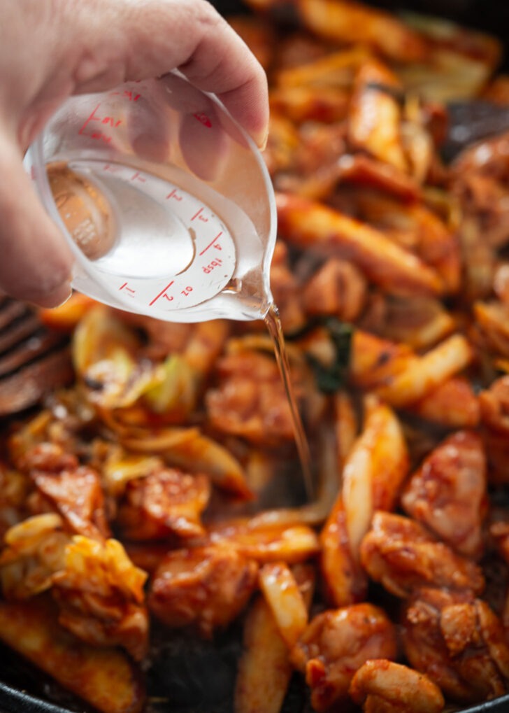 Water is added to stir-fried chicken and vegetables.