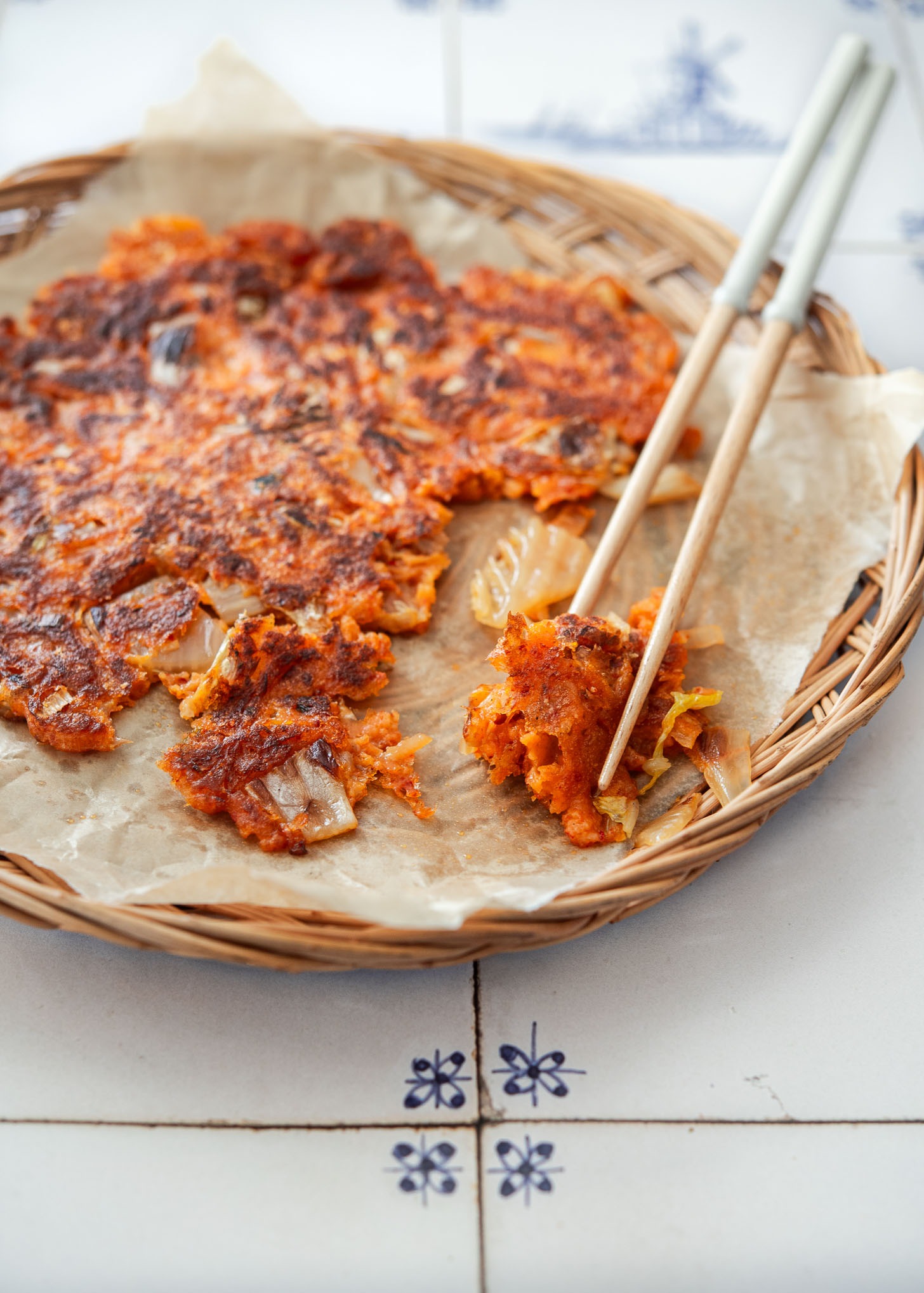 Chopsticks holding a piece of crispy kimchi pancake.