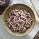 Bowl of purple Korean multigrain rice (japgokbap) with a spoon, showing color from black rice.