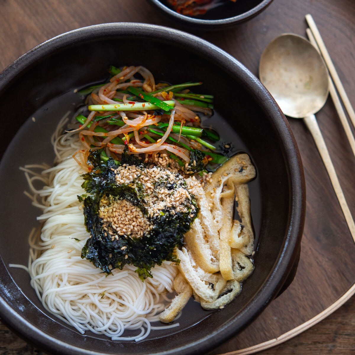 Bowl of janchi guksu, Korean wheat noodles in anchovy broth with vibrant toppings.