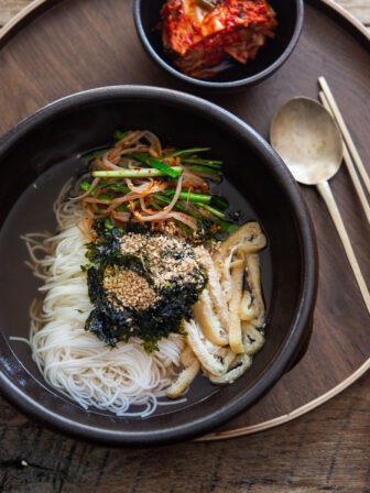 Bowl of janchi guksu, Korean wheat noodles in anchovy broth with vibrant toppings.