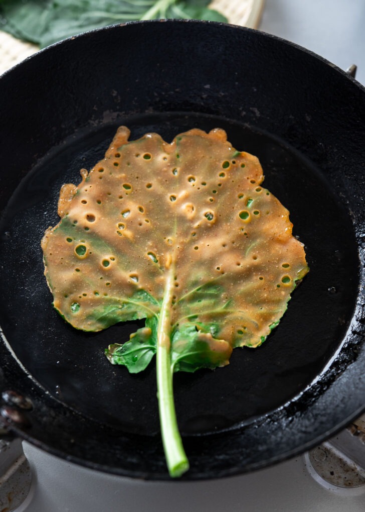 Kale jangtteok frying in a skillet until golden and crispy