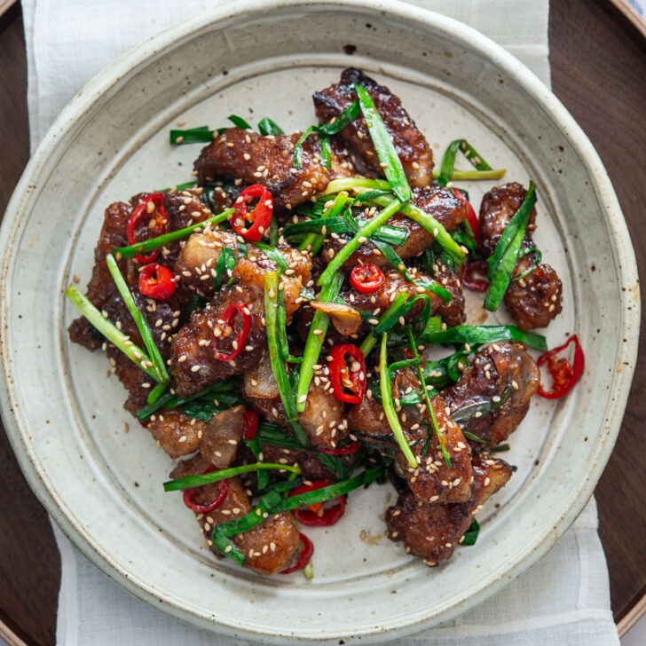 Honey garlic pork with chives in a serving plate.