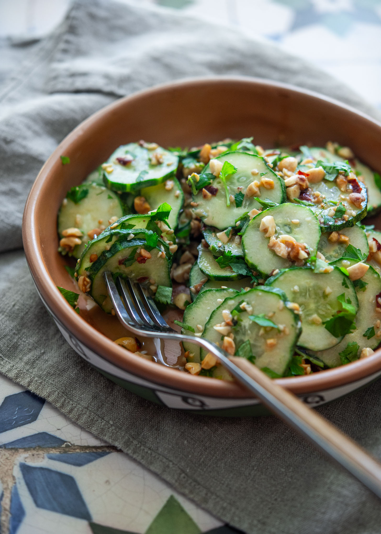 Close-up of peanut cucumber salad with creamy dressing and a fork ready to serve