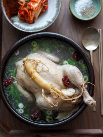 Samgyetang (Korean whole chicken soup) garnished with ginseng in a serving bowl