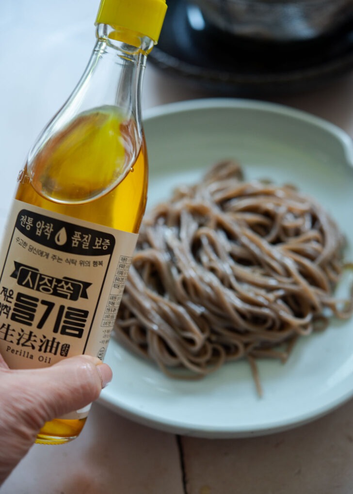 Drizzle perilla oil over the buckwheat noodles in a serving dish.