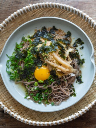 Makguksu with perilla oil, kimchi, and egg yolk in a dish.