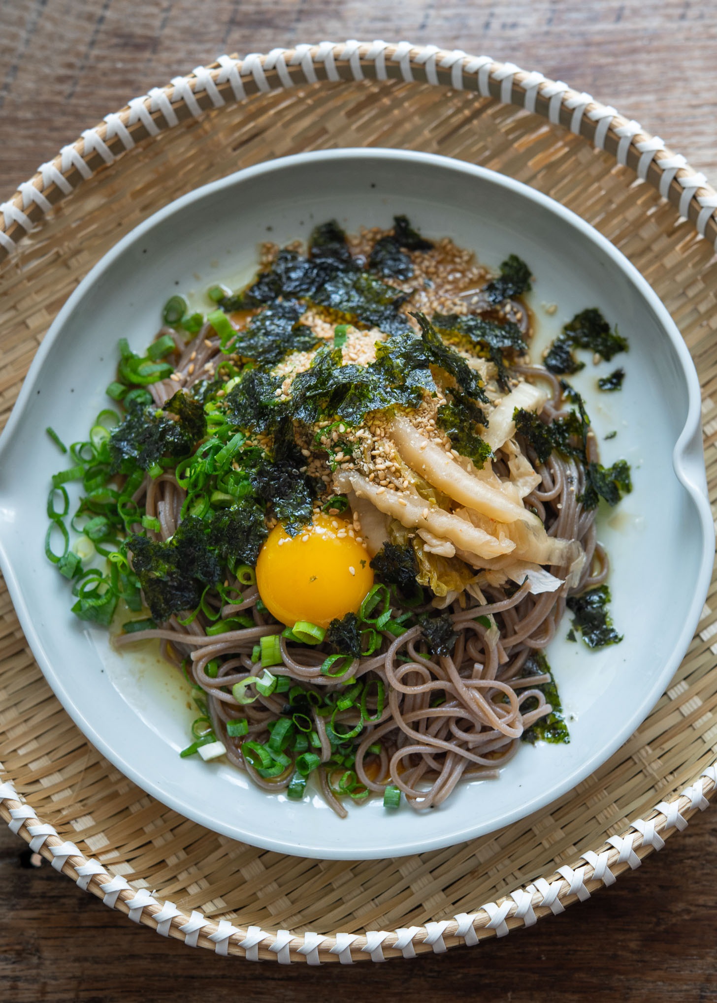 Makguksu with perilla oil, kimchi, and egg yolk in a dish.