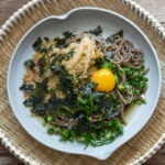 Makguksu with perilla oil, kimchi, and egg yolk in a dish.