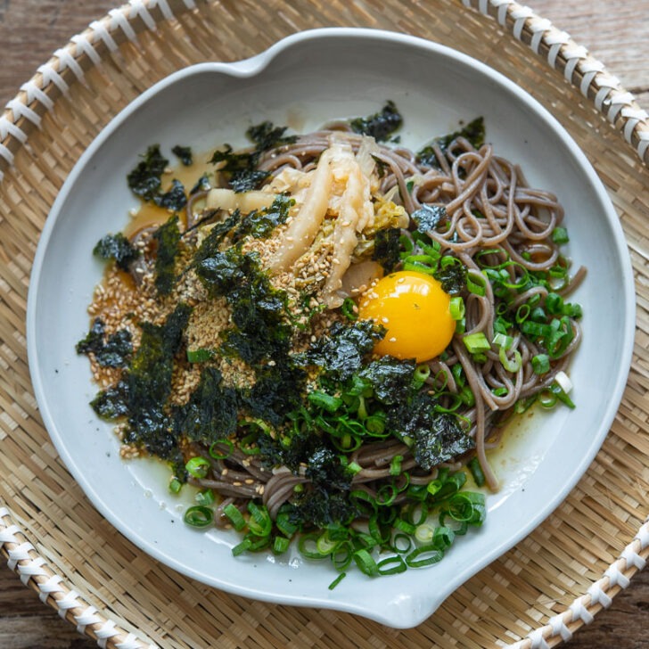 Makguksu with perilla oil, kimchi, and egg yolk in a dish.