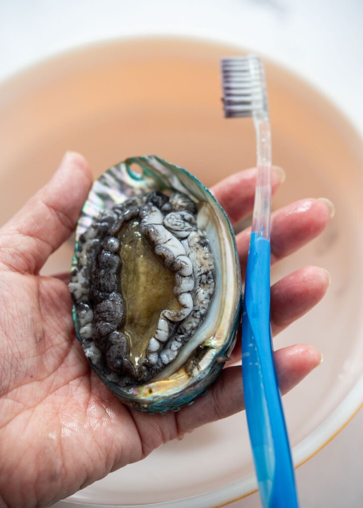 Brushing the lips of fresh abalone with a toothbrush.