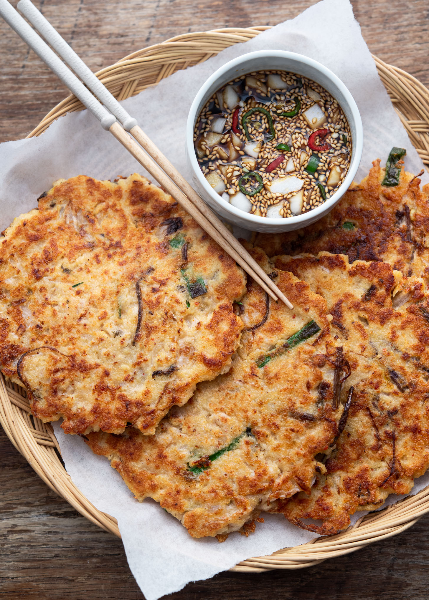 Korean mung bean pancakes arranged on a basket with dipping sauce