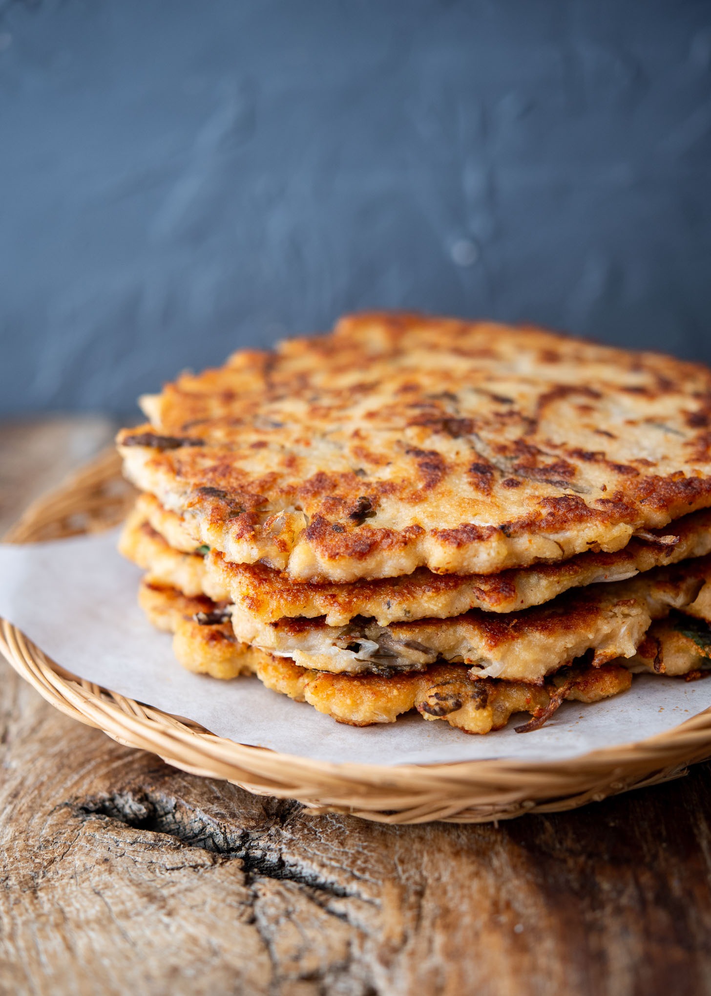 Stack of crispy bindaetteok on a wooden woven platter