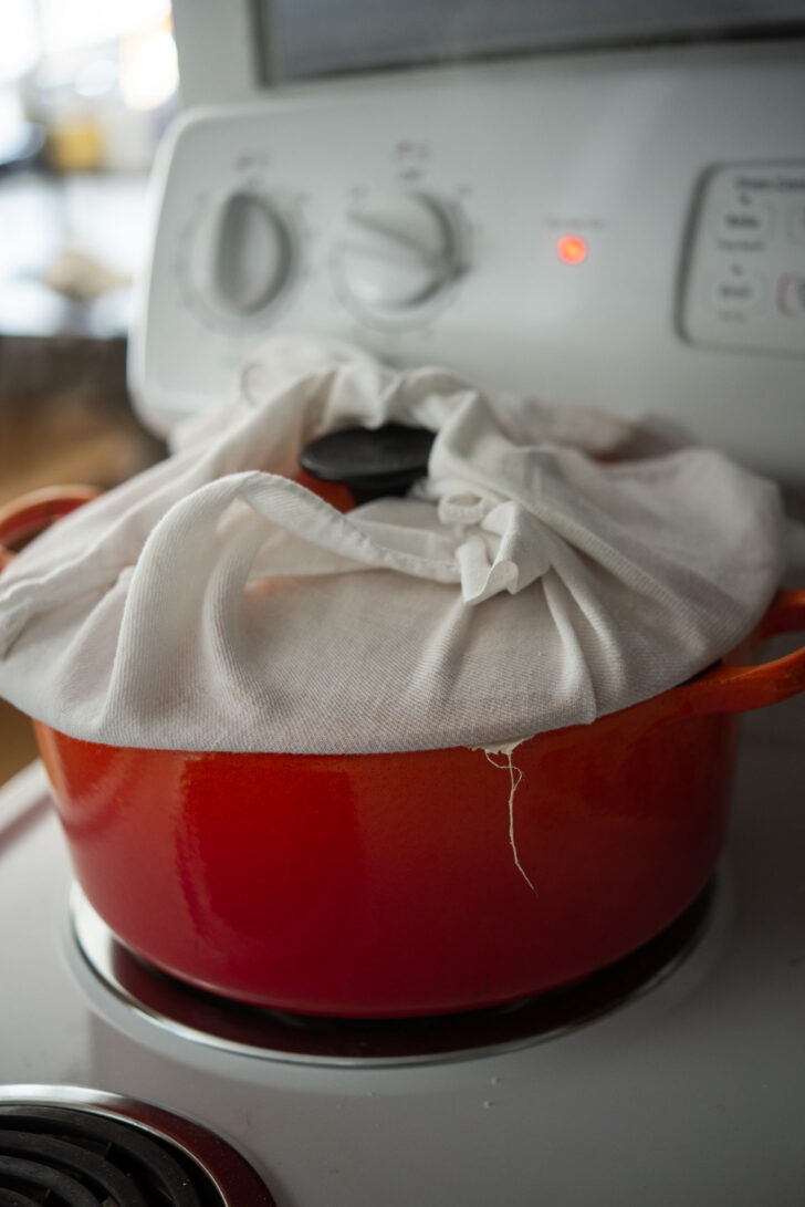 Steaming ssuk beouri in a pot with a cloth covered lid