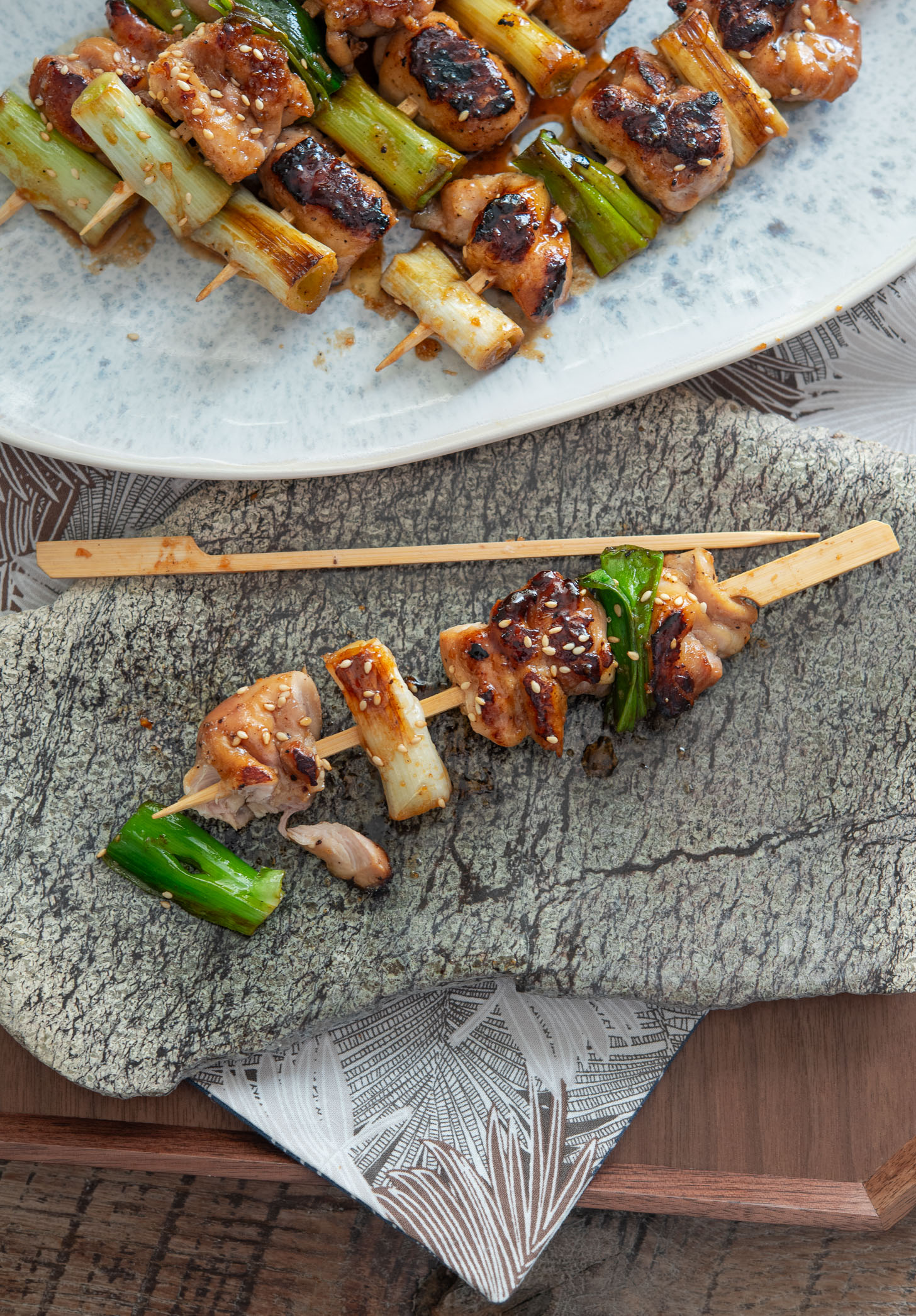 Close-up of glazed dakkochi skewer with chicken and charred daepa on a plate