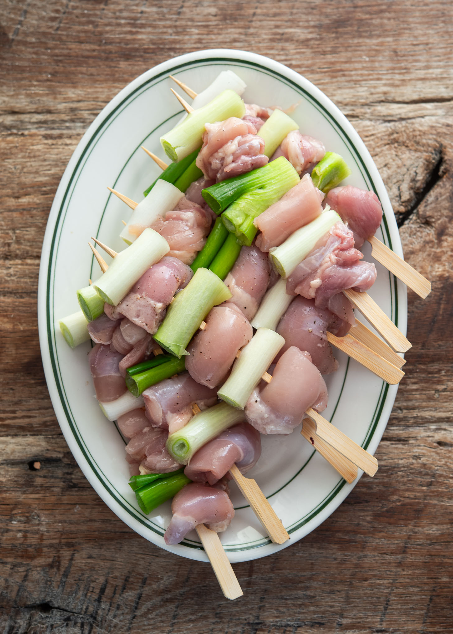 Chicken thigh and daepa (Korean leek) pieces threaded on skewers for dakkochi