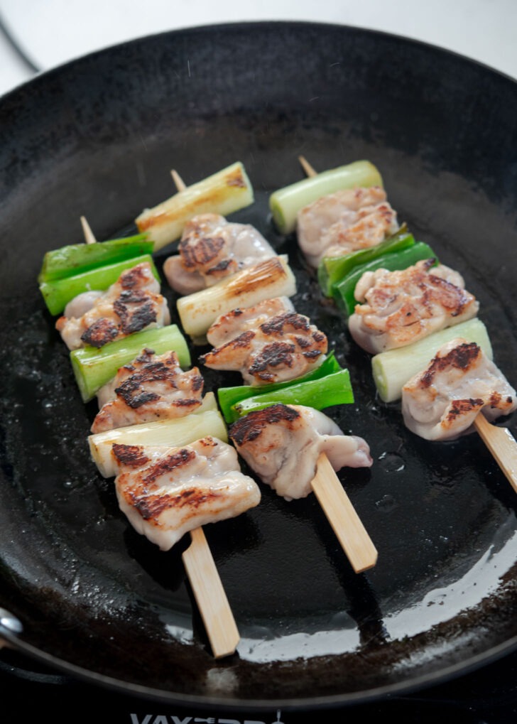Dakkochi chicken skewers searing in a hot skillet