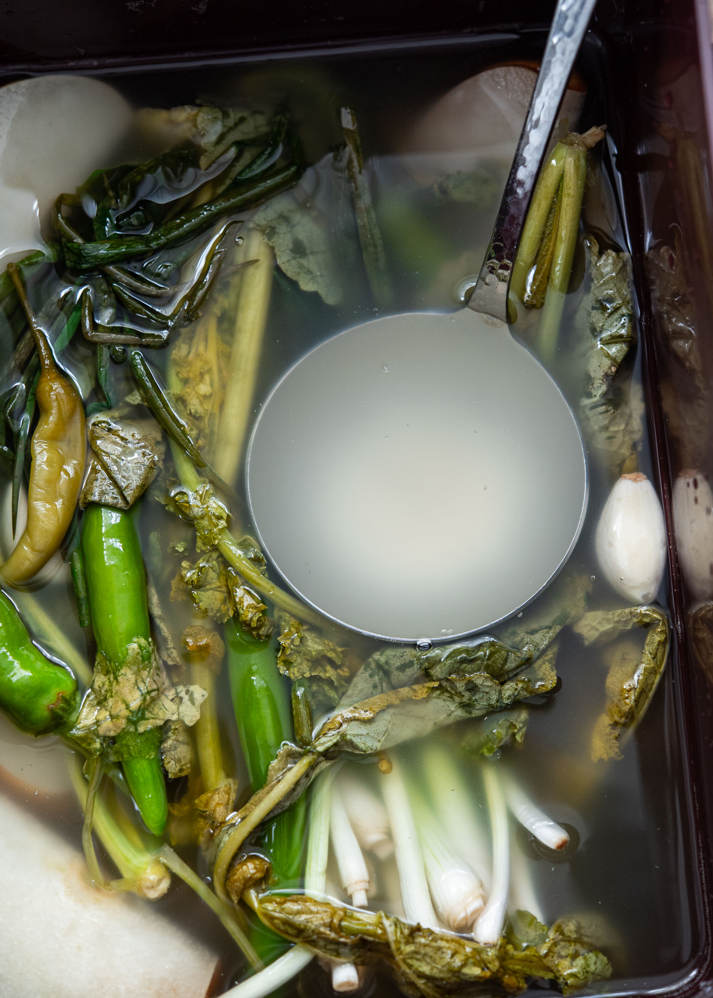 Clear, fermented dongchimi brine scooped in a ladle