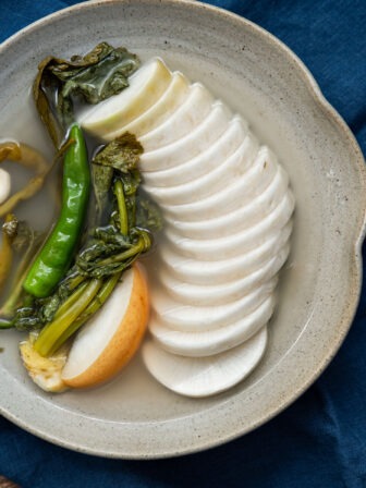 Dongchimi served in clear chilled brine with sliced Korean radish and greens