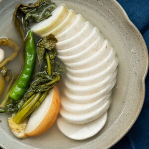Dongchimi served in clear chilled brine with sliced Korean radish and greens