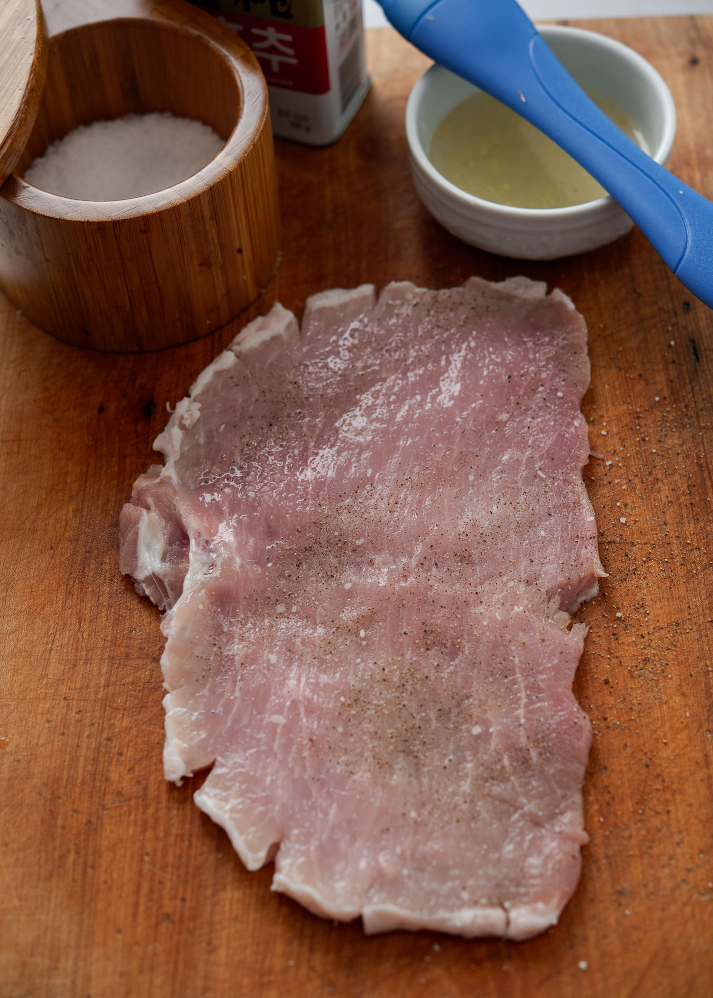 Seasoning thin pork loin cutlet with salt and pepper before breading