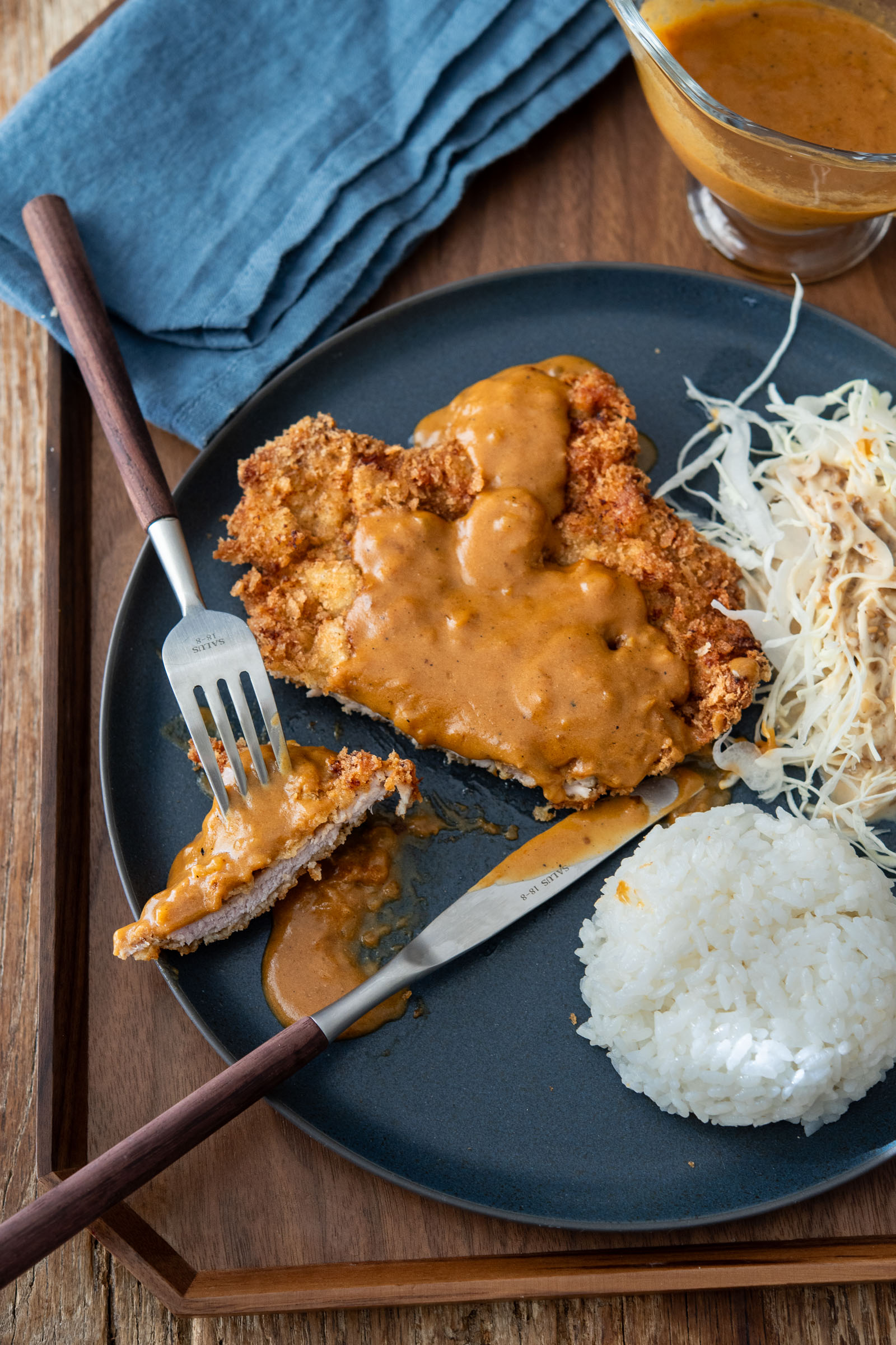 Crispy Korean donkatsu cutlet with brown sauce served with rice and cabbage