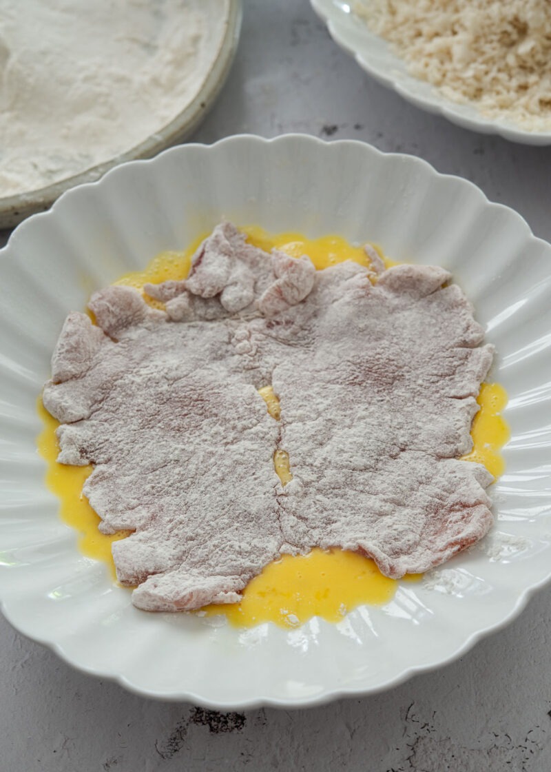 Coating floured pork cutlet in beaten egg for Korean donkatsu