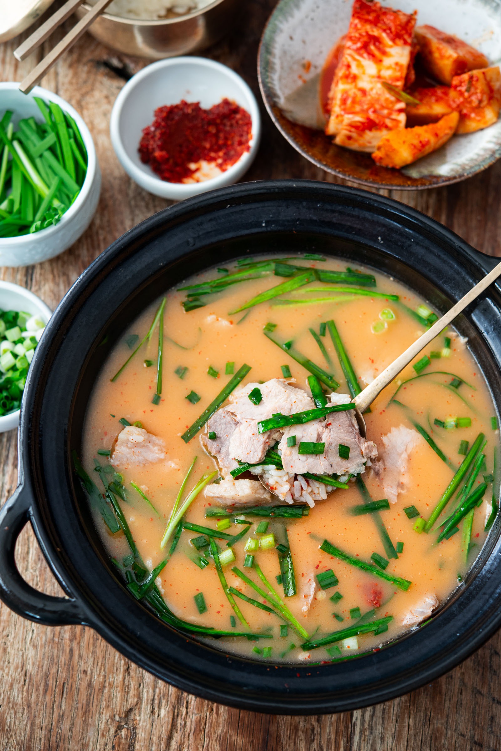 Thin slices of pork on a spoon in a bowl of dwaeji gukbap