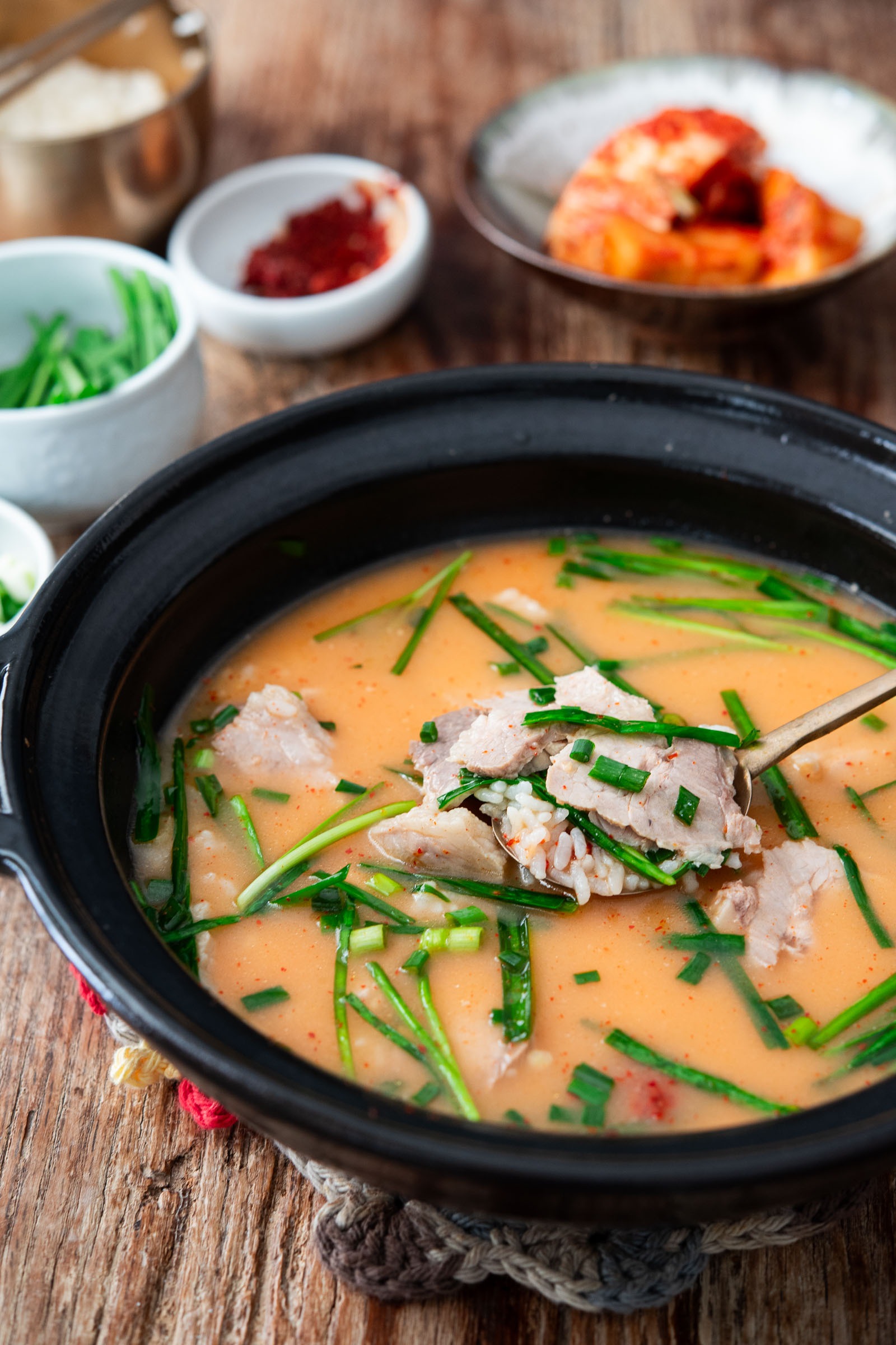 A spoonful of dwaeji gukbap with bone marrow broth in a bowl