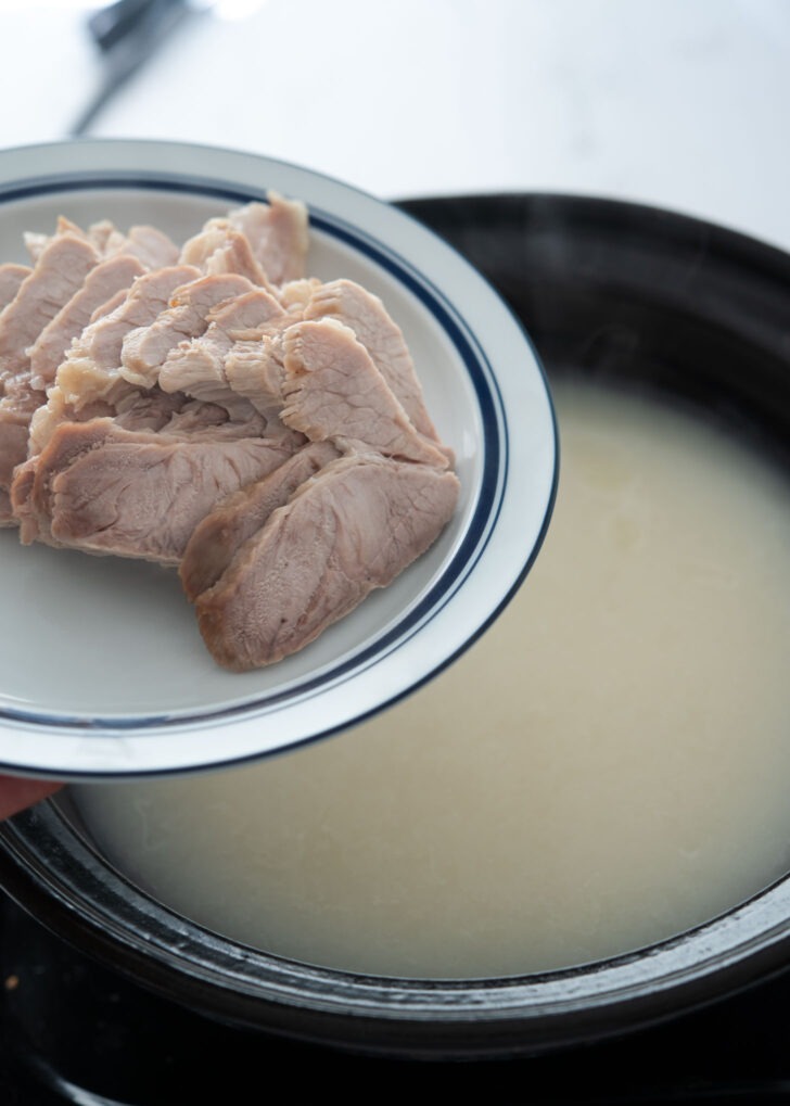 Sliced pork shoulder adding in the bone marrow soup base