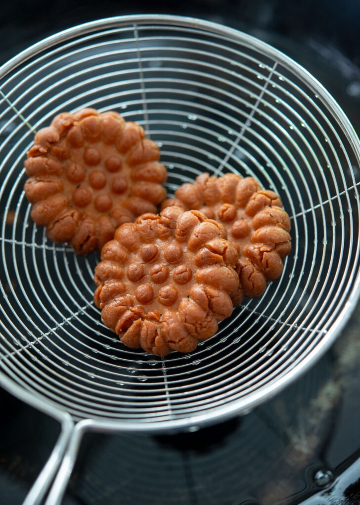 Draining excess oil from the fried cookies