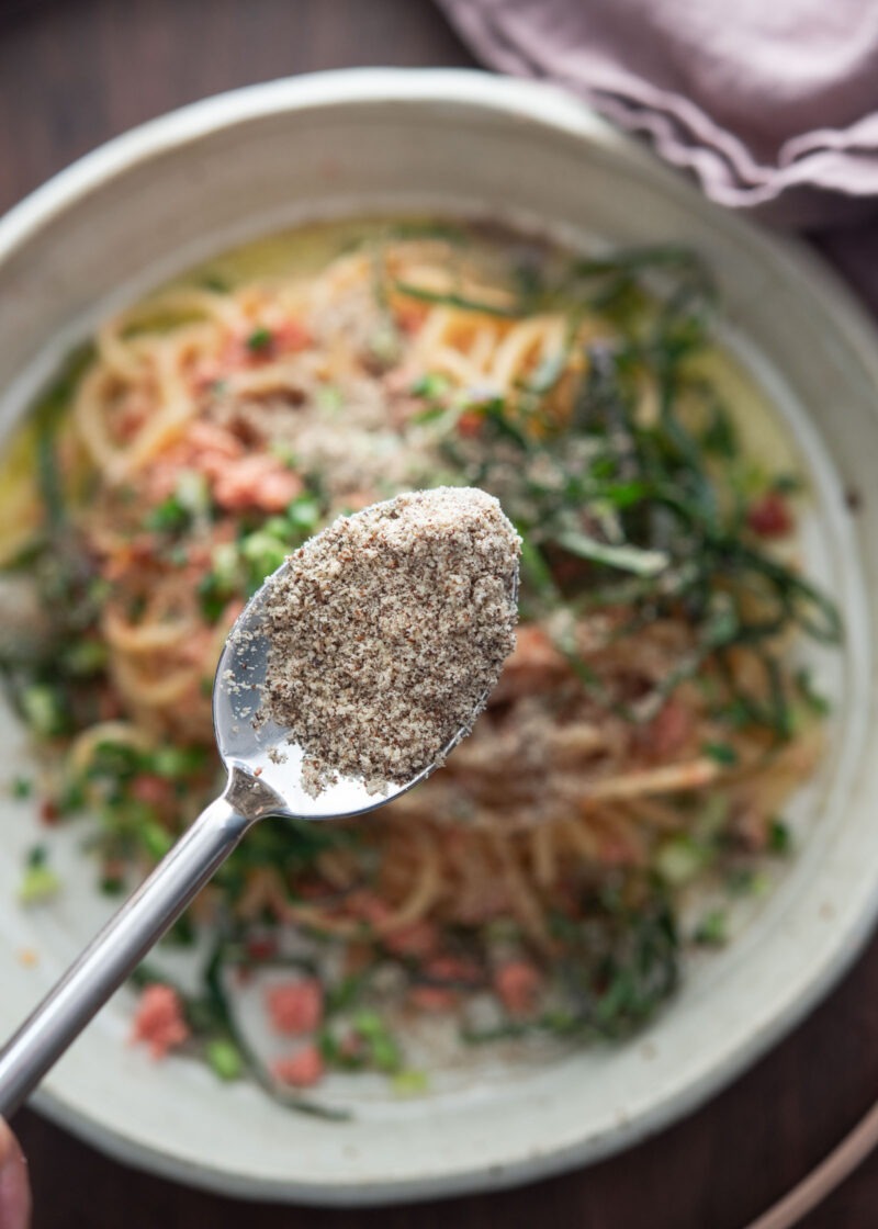 Ground perilla seeds on a spoon over mentaiko pasta