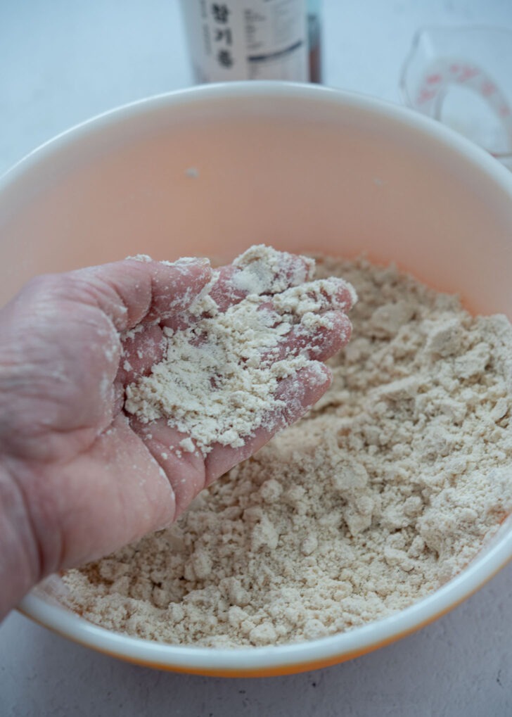 Rubbing the flour mixture with sesame oil to form fine crumbs