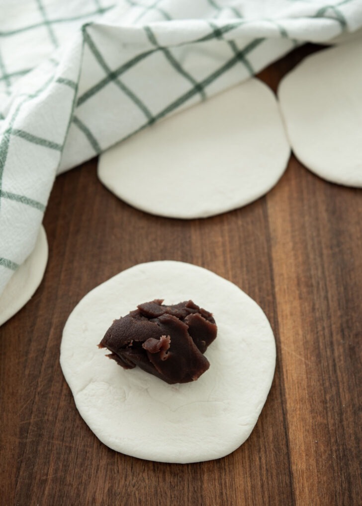 Placing sweet red bean filling in the center of flattened hoppang dough
