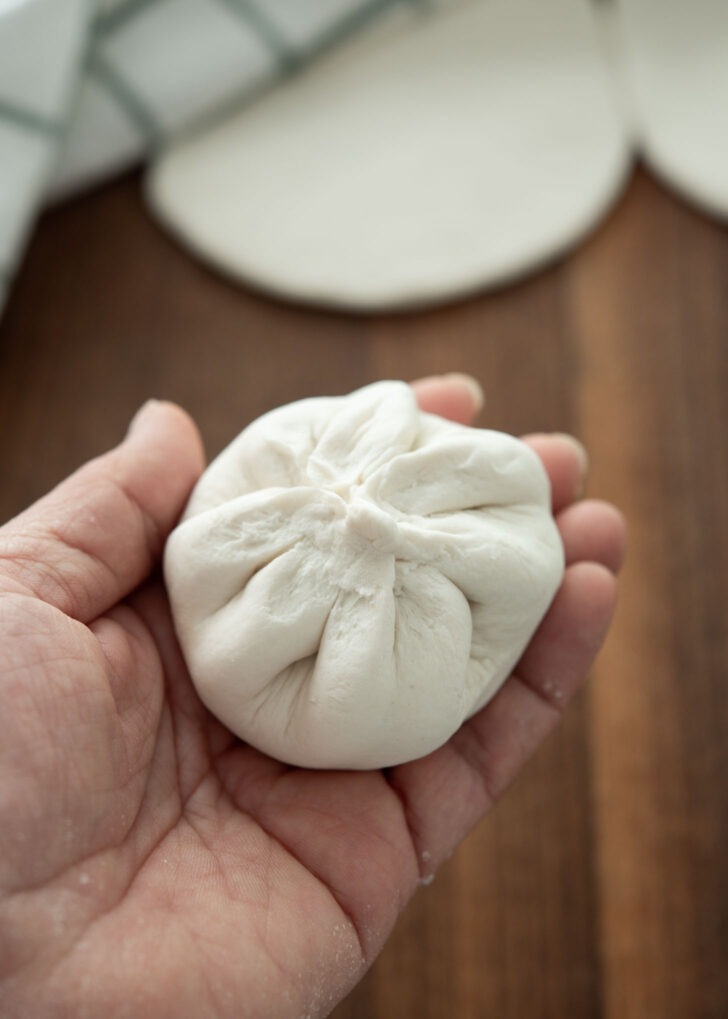 Pinching the bottom of the dough to seal the hoppang bun