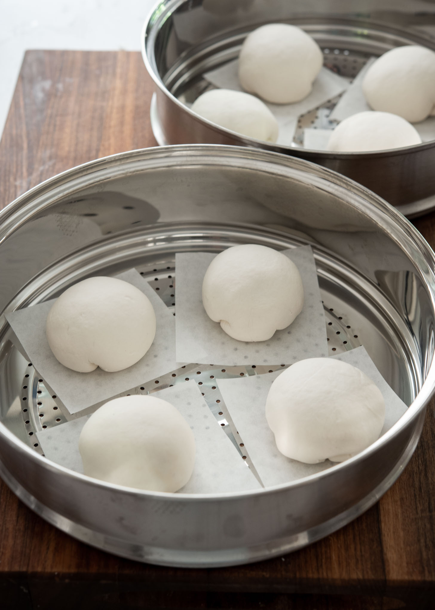 Placing shaped hoppang buns in a steamer tray to rise before cooking